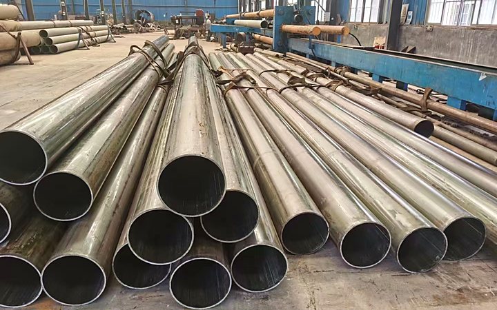 Rows of alloy pipe and fittings staged in an outdoor yard before shipment
