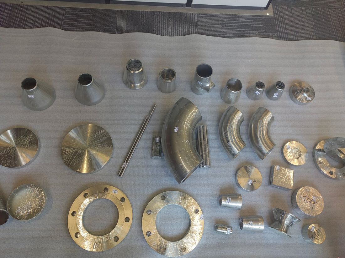 Butt weld elbows, reducers, caps and flanges laid out for dimensional inspection